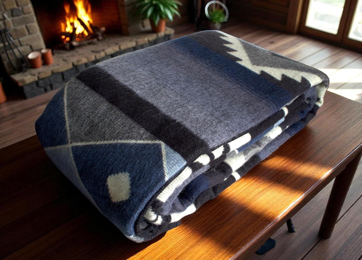 Folded blue and white patterned blanket on a wooden table with a fireplace in the background